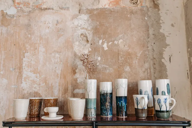 A row of handmade decorated cups, sized with the help of a clay shrinkage calculator so a set finishes the same height.