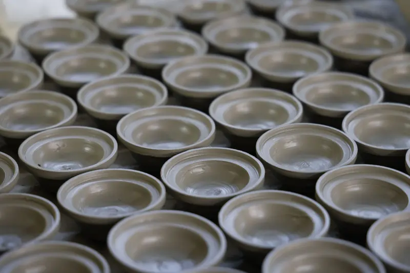 Rows of handmade clay bowls ready for the kiln, with the kiln electricity cost shared across every piece in the load.