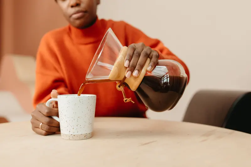 Coffee being poured into a speckled handmade mug, whose capacity a mug and bowl size converter works out from its inside size.