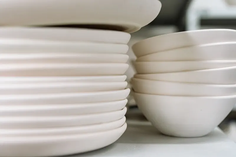 Stacked handmade bowls and plates, the kind of pieces a mug and bowl size converter helps you size by capacity.