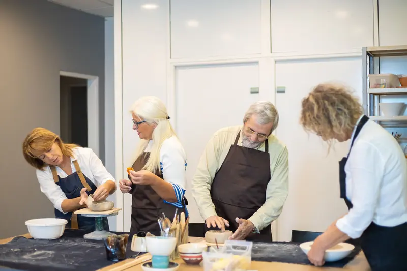 A group making bowls together in a pottery workshop, the kind of session a pottery class cost estimator budgets for.