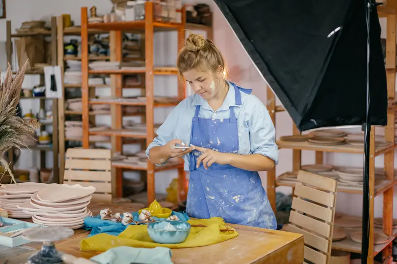 A potter working alone in a creative studio, weighing up studio hire cost against owning a setup.
