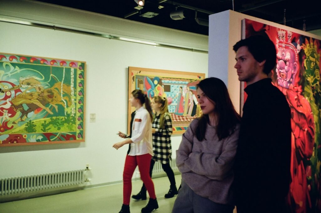 Visitors viewing paintings at a small gallery exhibition