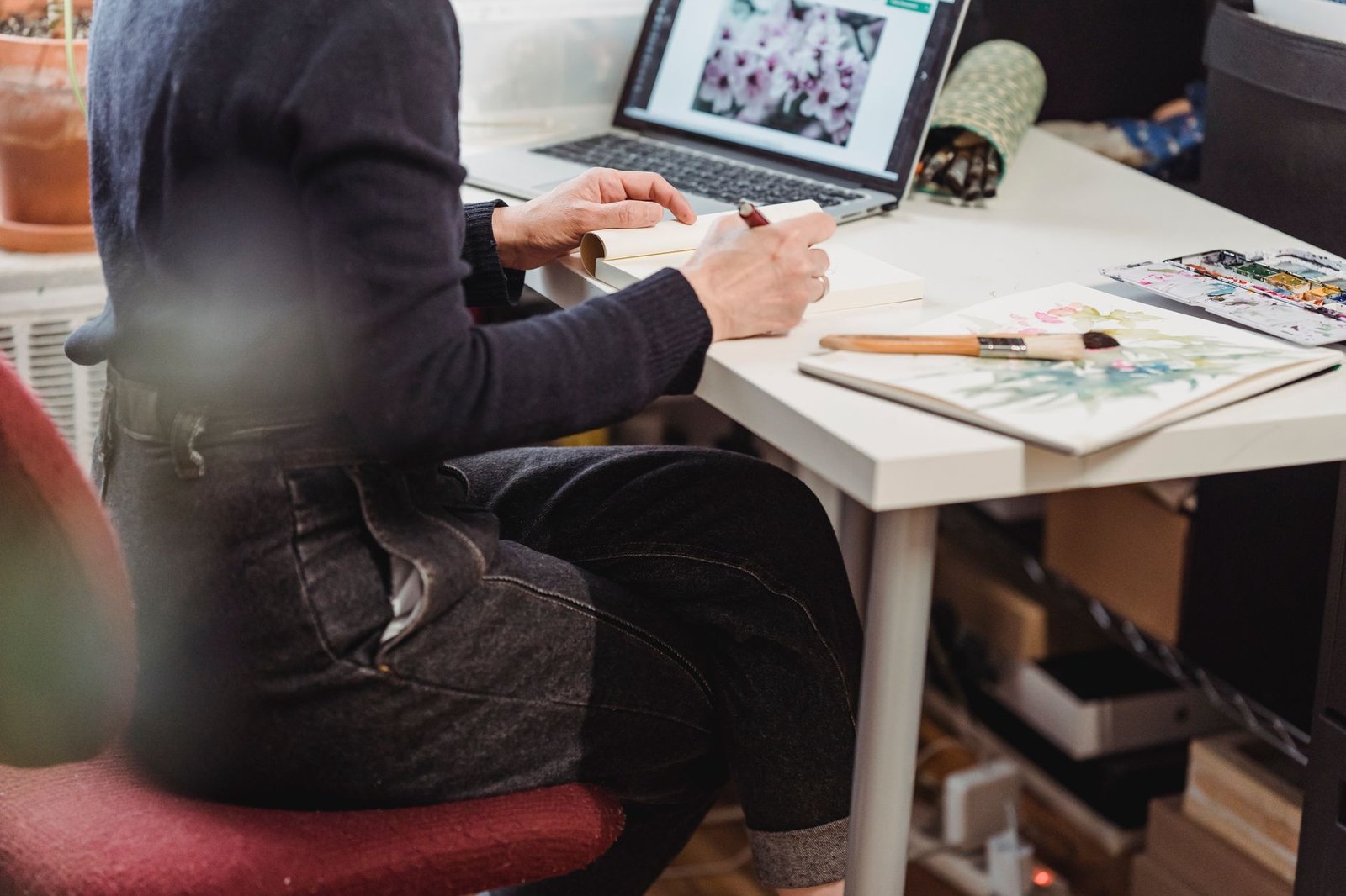 Artist sketching and painting at a studio desk