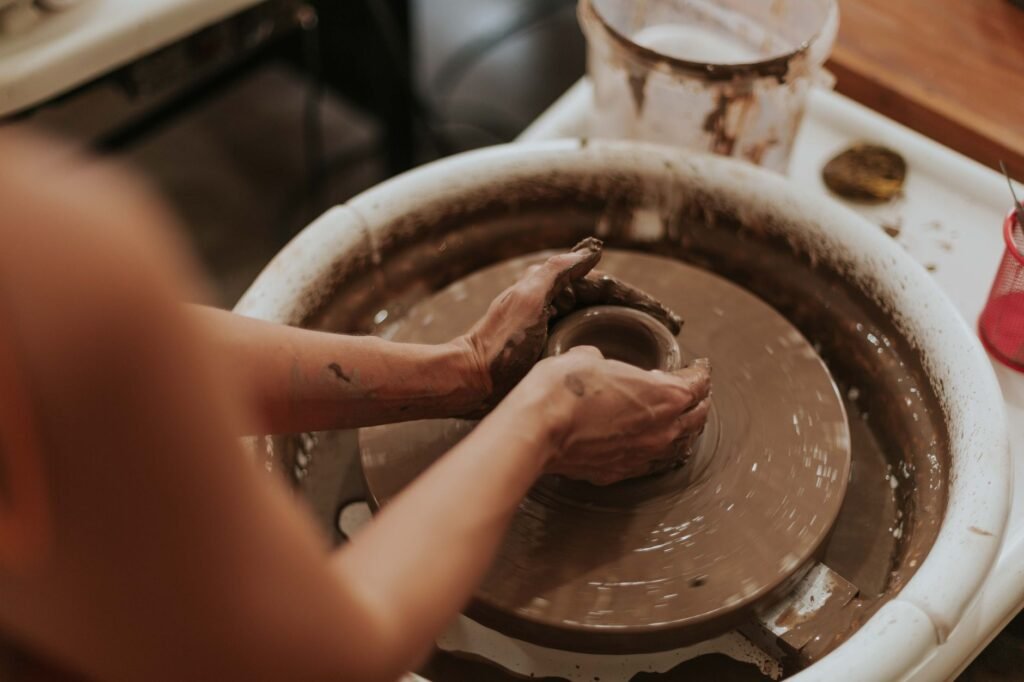 Hands shaping clay on a pottery wheel
