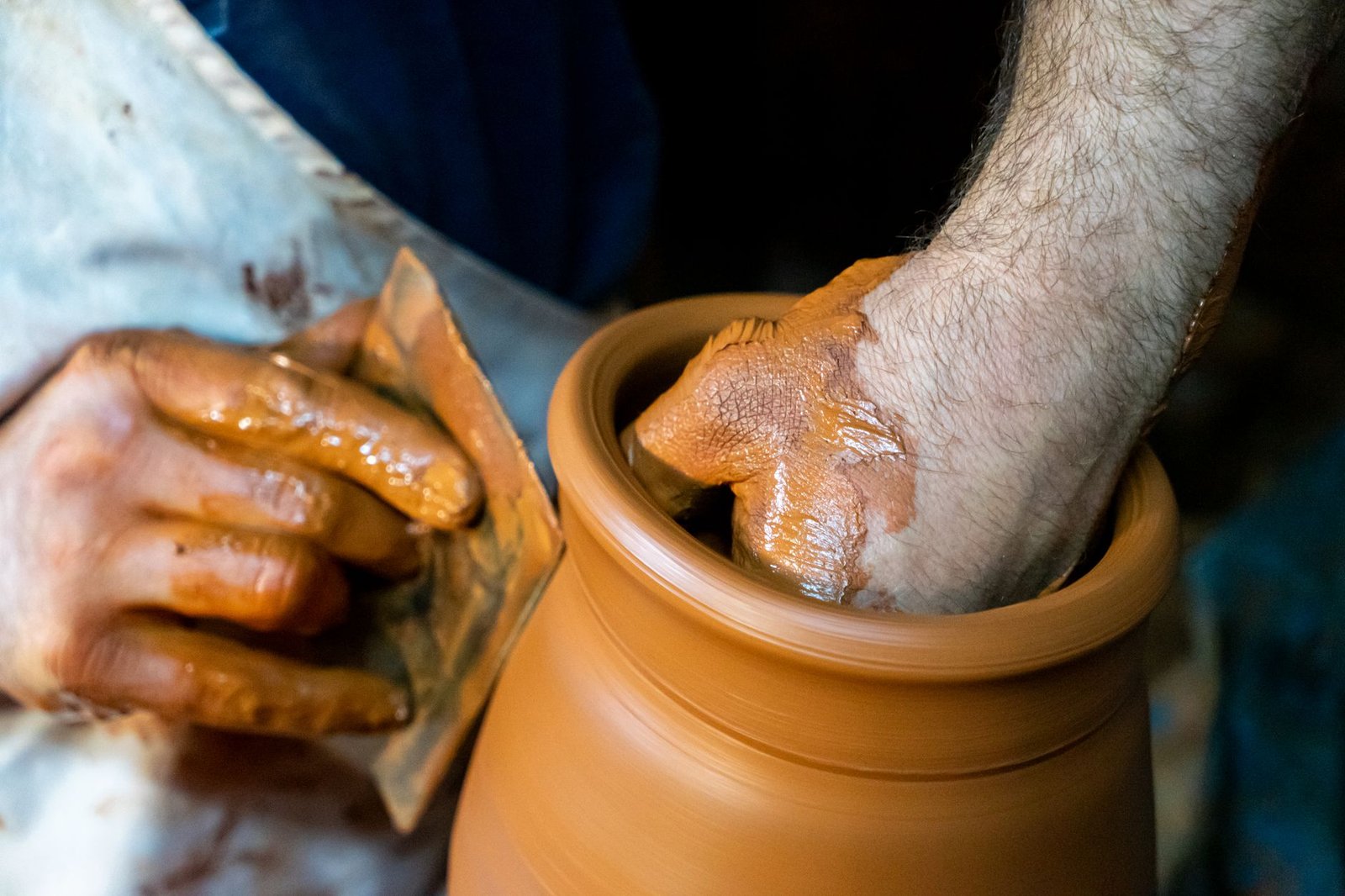 Hands shaping clay on a pottery wheel