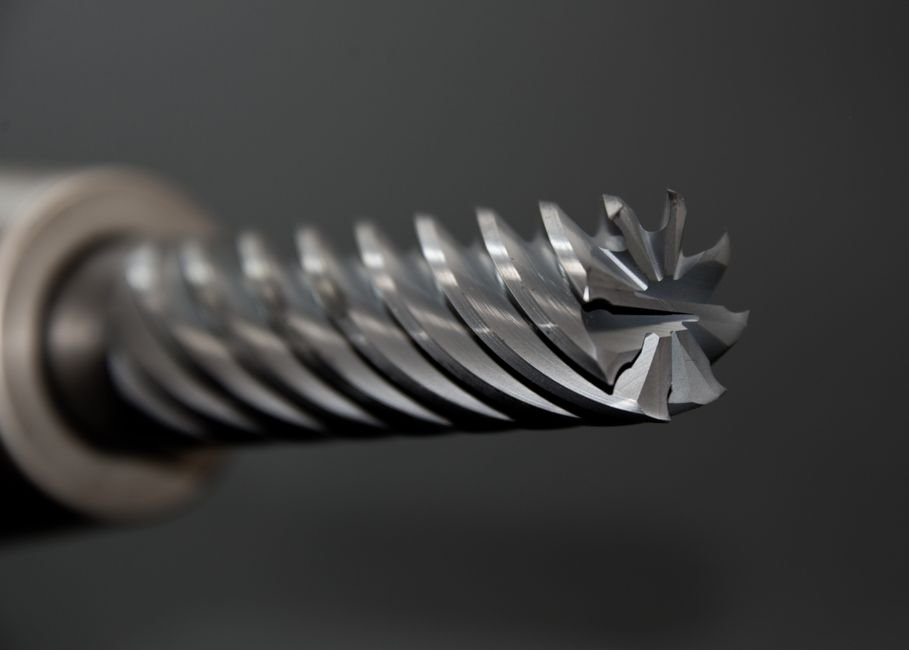 Close up of a diamond drill bit beside finished ceramic pieces