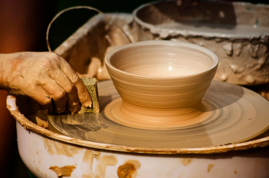 Artisan crafting pottery on a potter's wheel with a wet sponge