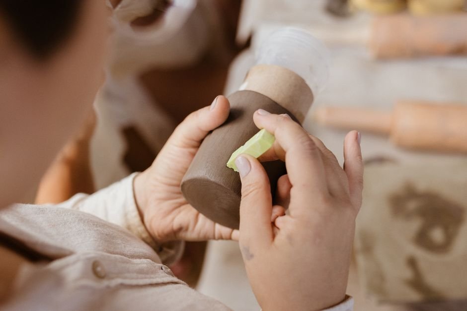 Long handled sponge tool reaching inside a ceramic vase