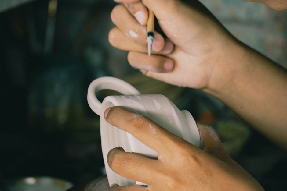 Fan brush applying crystal glaze to bisque ceramic surface