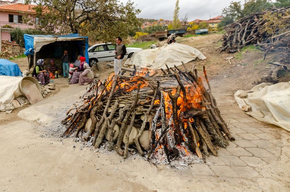 Group gathered around a traditional pottery firing process outdoors