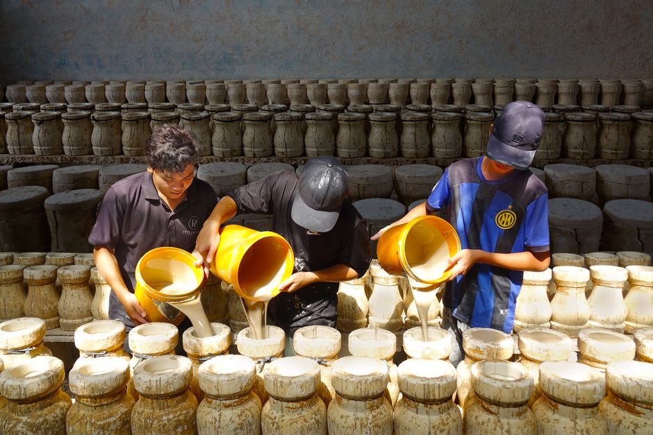 Potter pouring liquid casting slip into a plaster slip mold