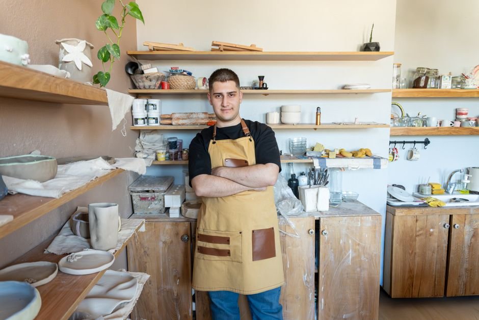 Potter standing in a ceramic workshop surrounded by pottery tools