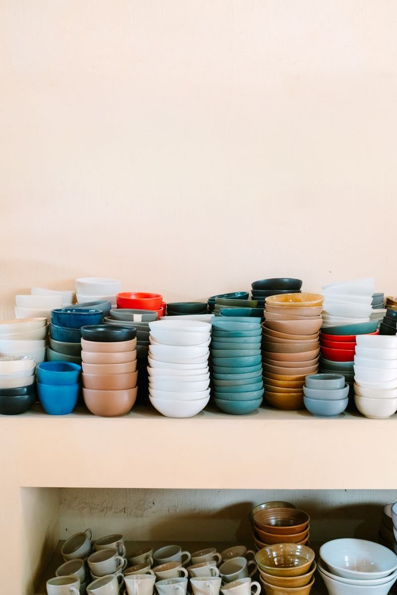 Colorful glazed ceramic bowls on a pottery studio shelf