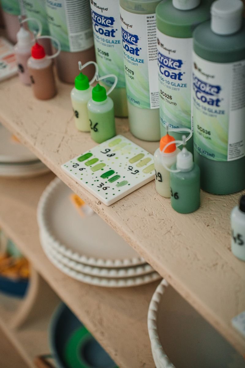 Colorful Mayco glaze bottles on a pottery studio shelf