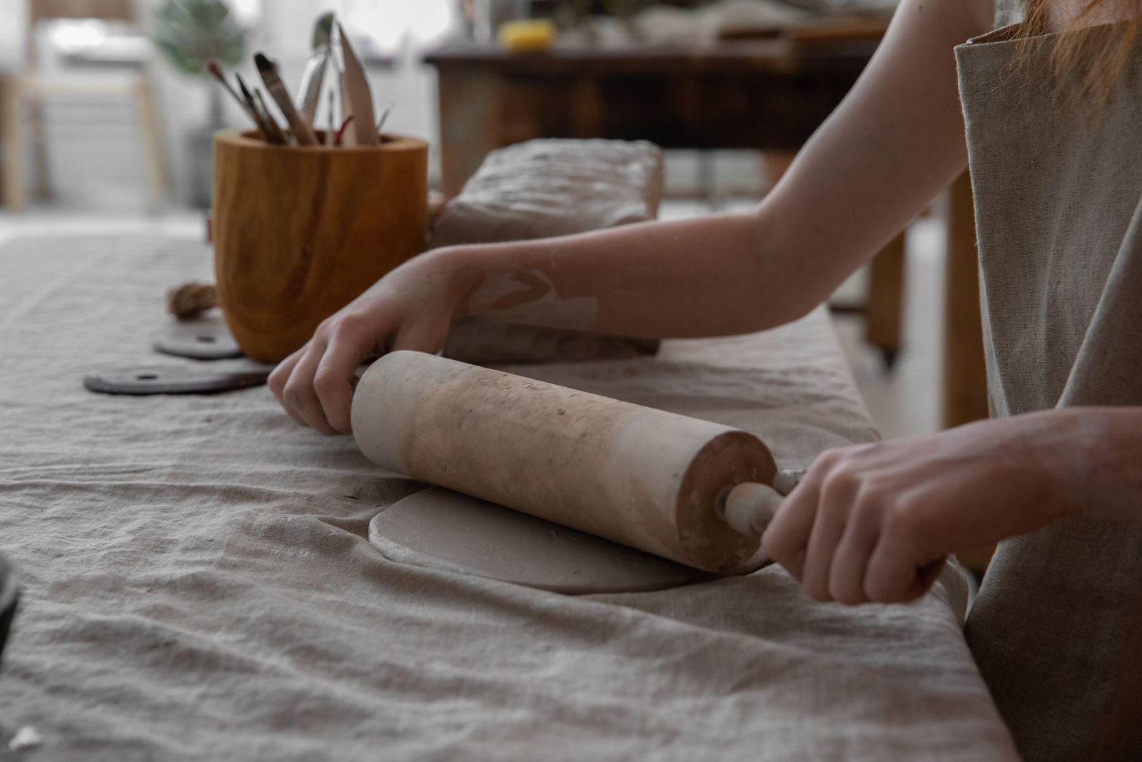 Hands using a pottery rib tool to shape clay