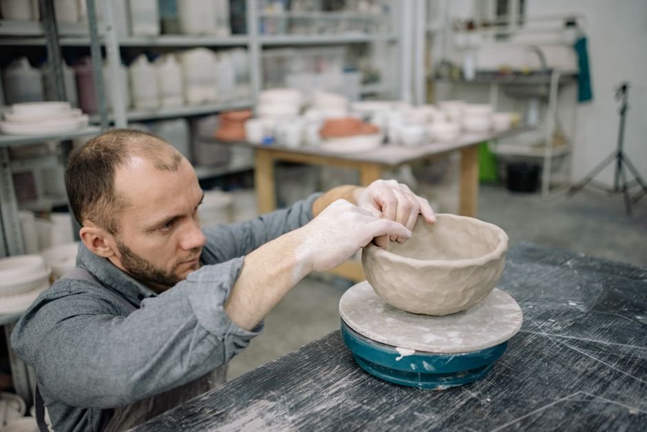 Man shaping a clay bowl in an artisan pottery studio workshop