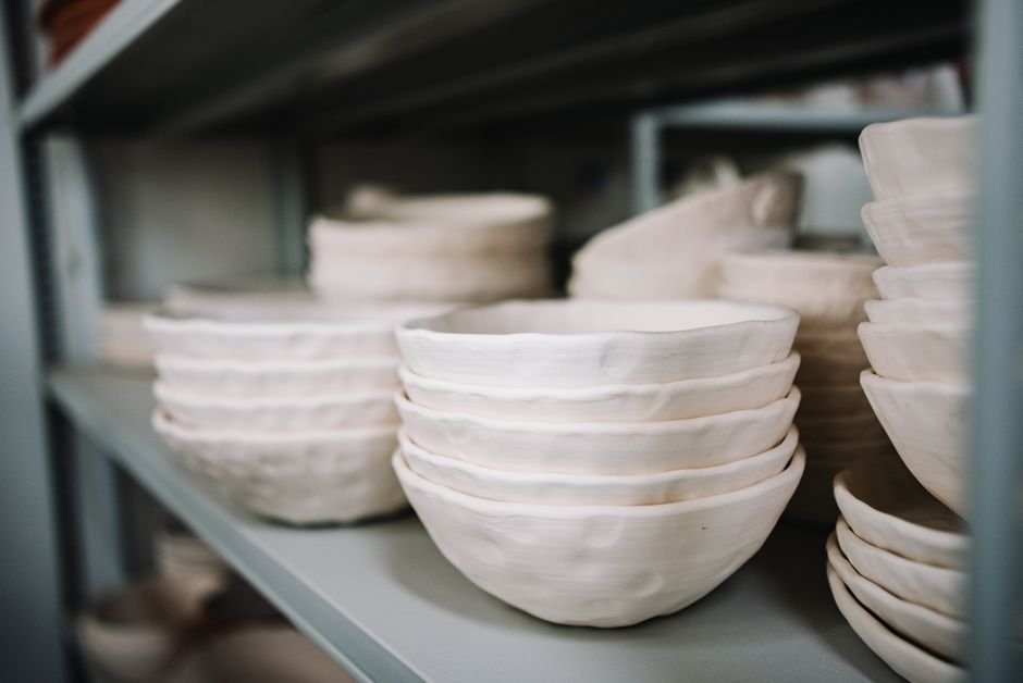 Finished stoneware pottery pieces beside the kiln at a ceramic studio