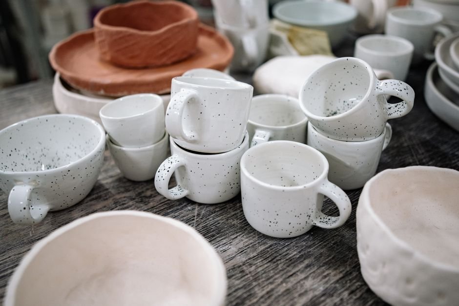 Artisan pottery cups and bowls displayed on a rustic studio table