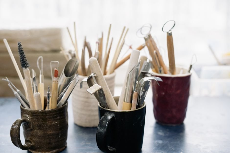 Collection of pottery tools organised in mugs on a workshop table