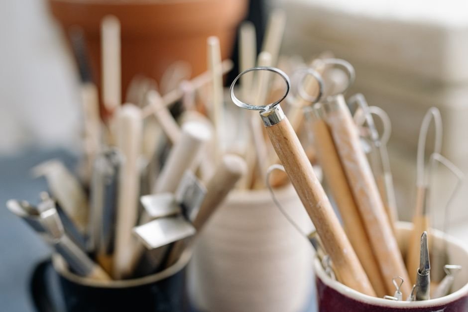 Beginner potter shaping clay on a wheel with simple tools