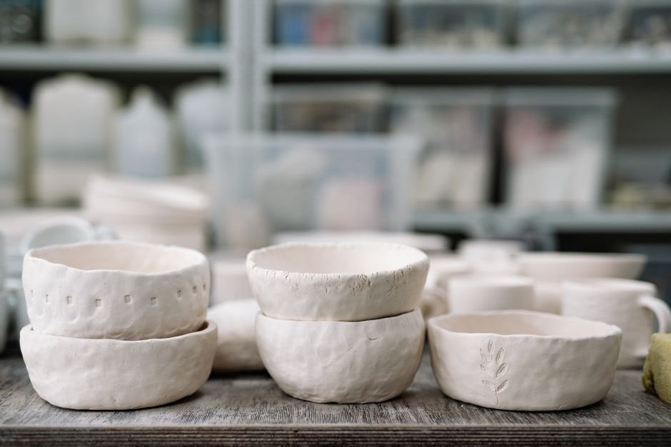Row of finished pottery pieces showing a consistent maker's stamp on the base