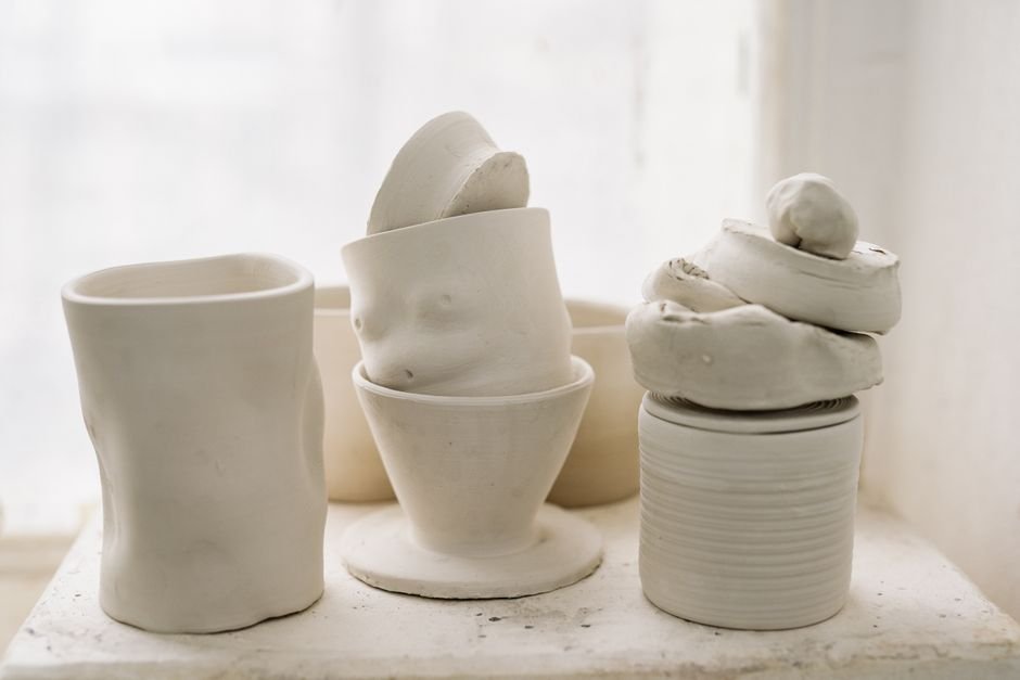 Minimalist still life of unglazed white pottery shapes on a shelf