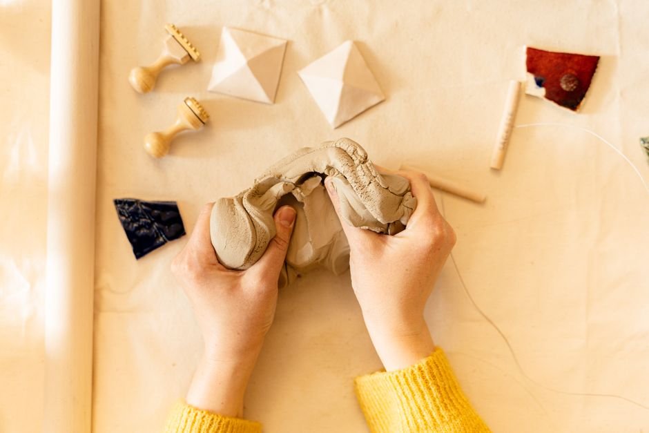 Hand pressing a carved ceramic stamp into soft clay