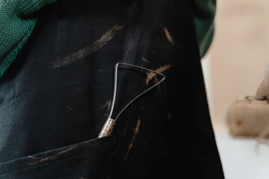 Sculpting tool held in an apron pocket closeup showing studio organisation