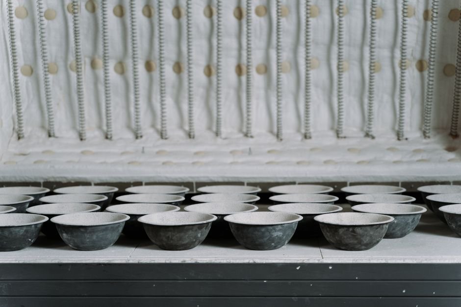 Ceramic bowls with glossy glaze arranged inside a kiln ready for firing