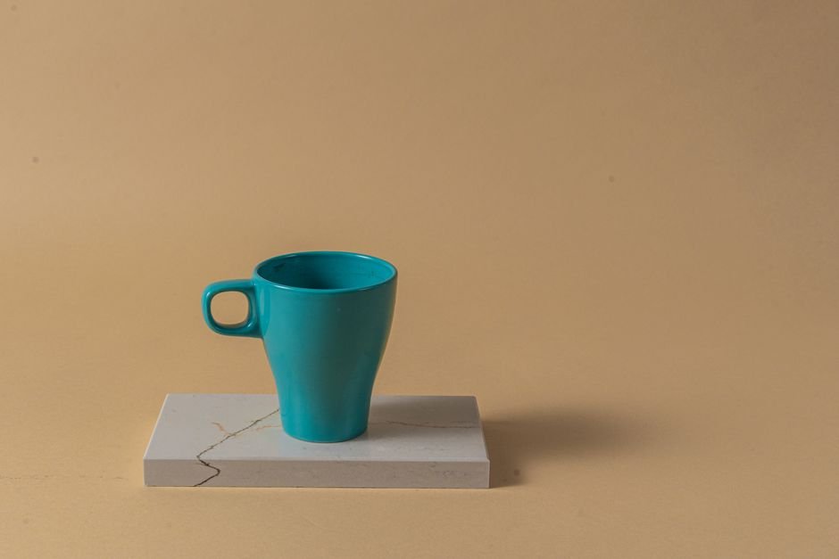 Teal ceramic mug with a glossy glaze finish placed on a marble surface