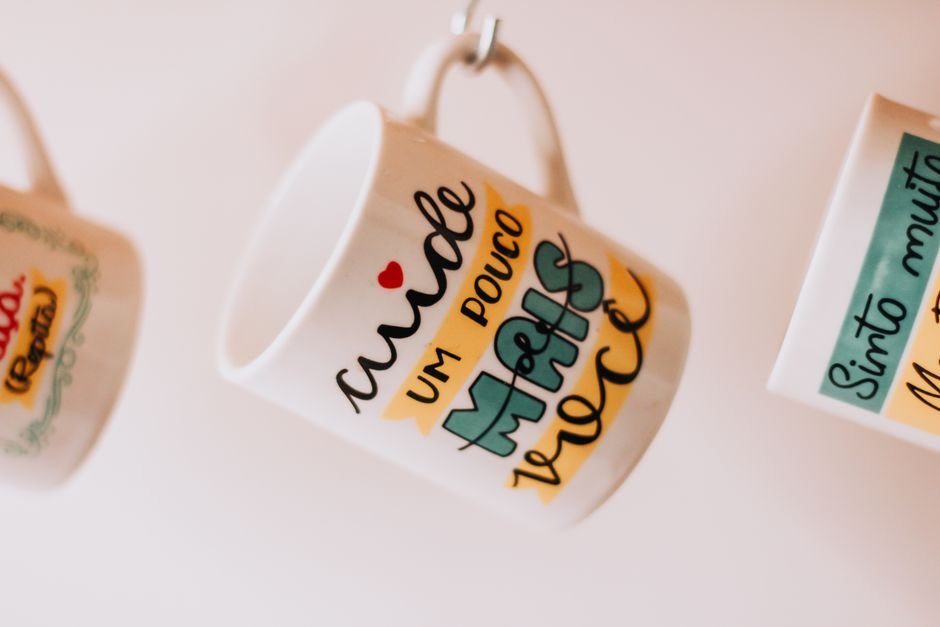 Hanging decorated ceramic mugs with text and pattern designs
