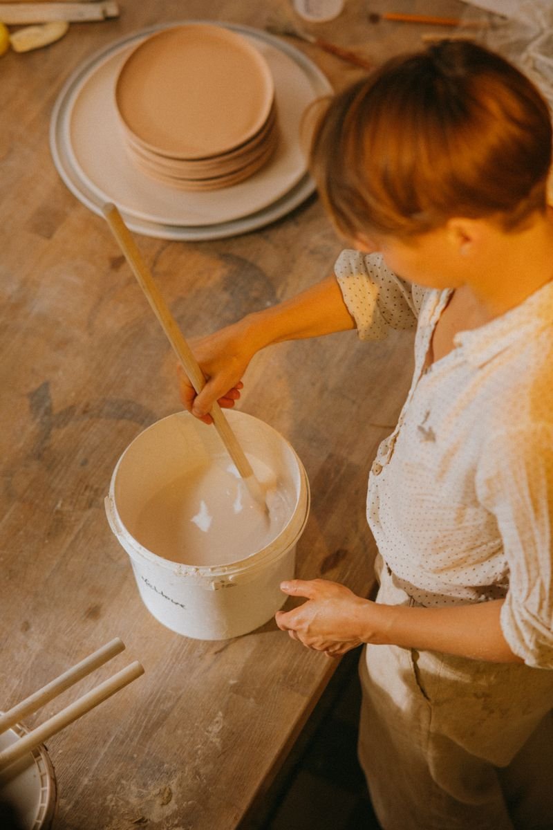 Assorted ceramic glazes in buckets in a pottery studio