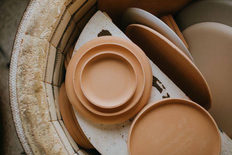 Rows of stoneware pottery pieces drying before the kiln firing