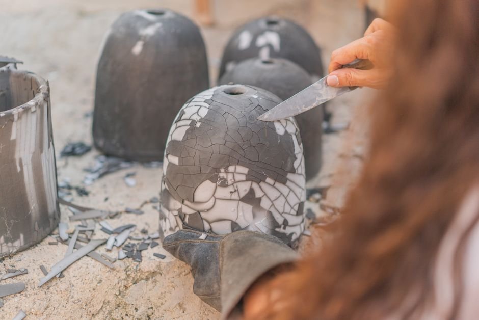 Artisan carving a clay pot, where a kneaded eraser helps lift crumbs from carved lines
