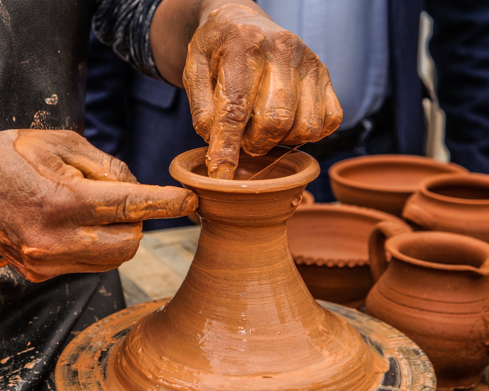 Hands shaping clay on a pottery wheel