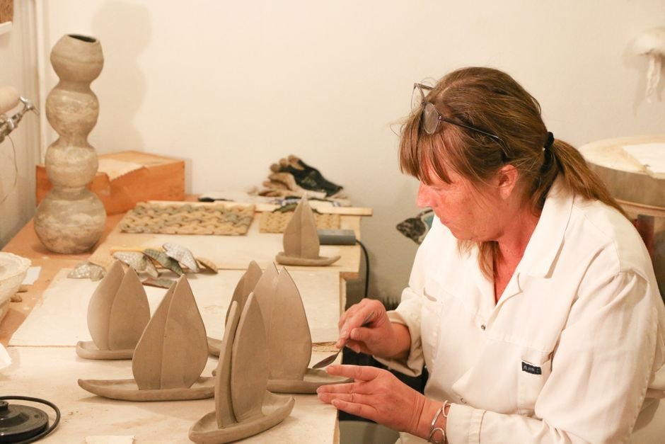 Woman crafting small ceramic sailboats, a playful example of clay art ideas beyond bowls and mugs