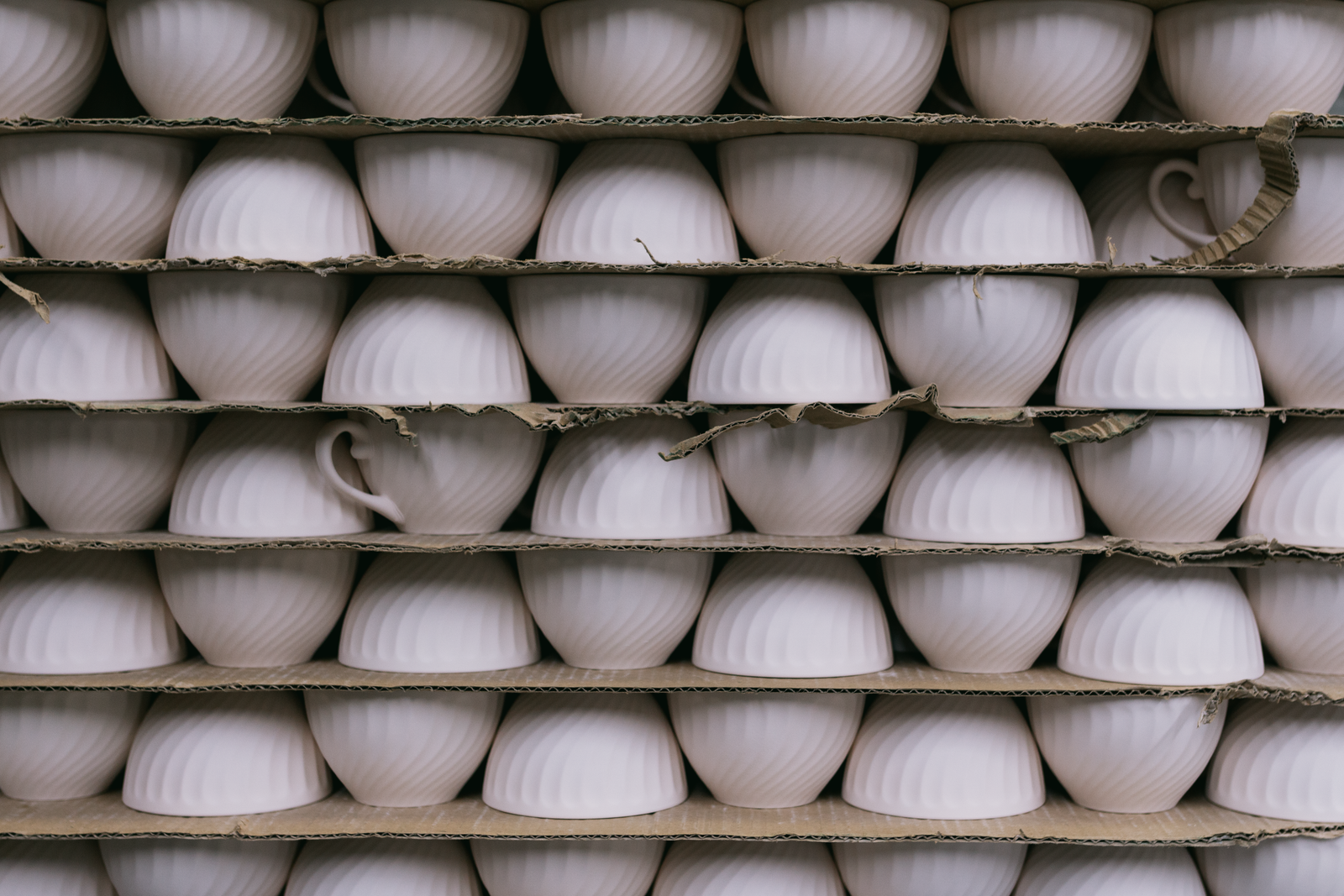 Unpainted bisque pottery pieces stored on a studio shelf