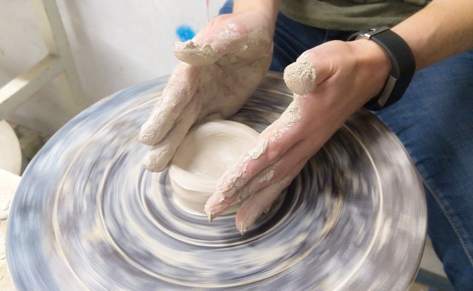 Potter's hands shaping clay on a spinning wheel, a technique central to the history of pottery