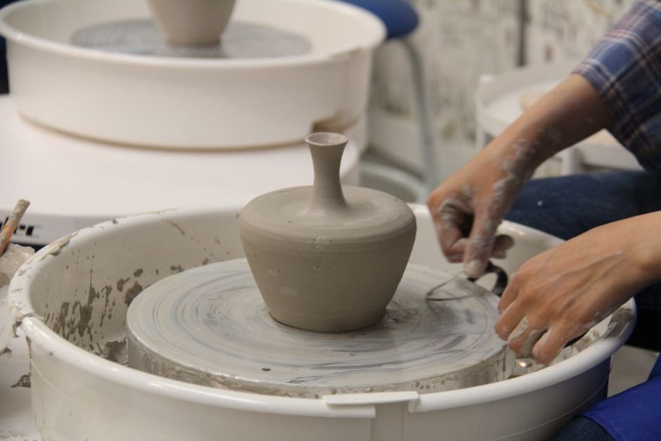 Hands shaping clay on a pottery wheel, a delicate process when throwing porcelain pottery