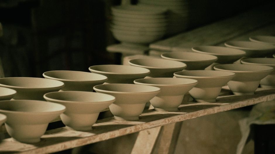 Unfinished ceramic bowls lined up in a workshop, part of the work stored under a pottery studio membership