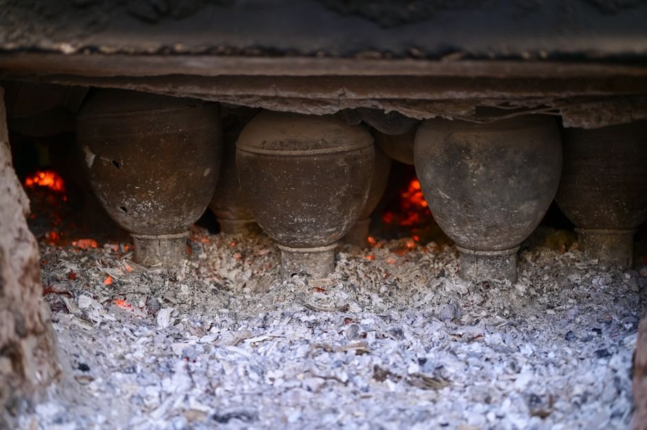 Clay pots firing in a traditional kiln with glowing embers, a setting where terra sigillata shines