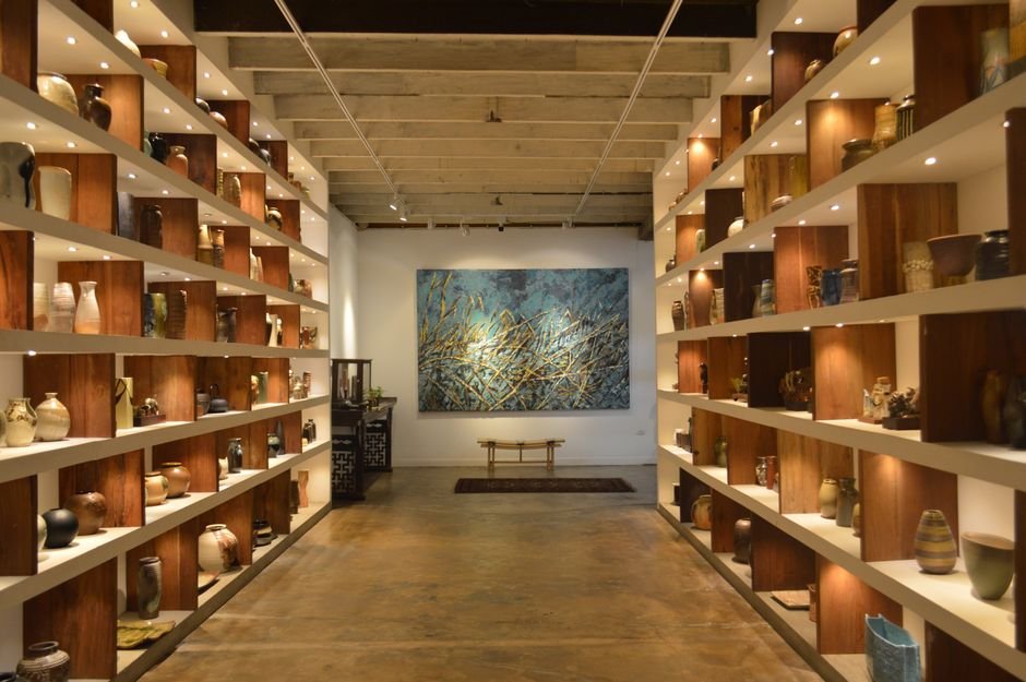 Collection of ceramic art pieces on gallery display shelves