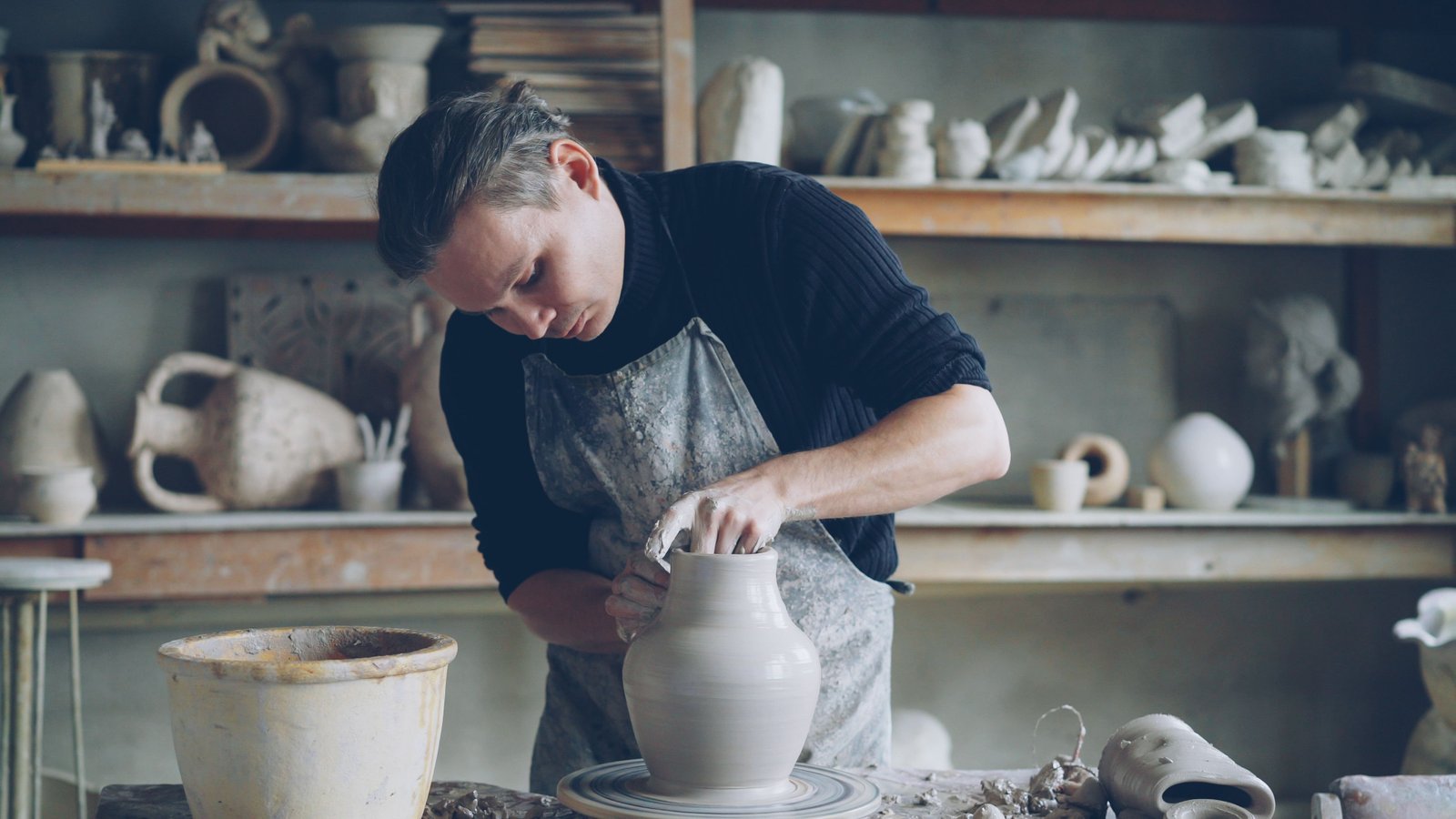 Potter shaping a piece on the wheel during a studio session