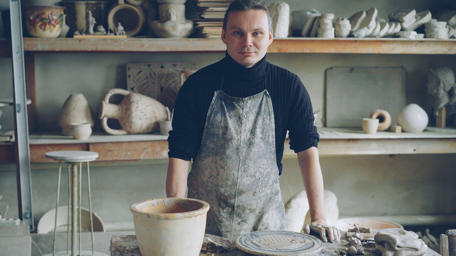 Craftsman working in a pottery studio surrounded by handmade ceramics