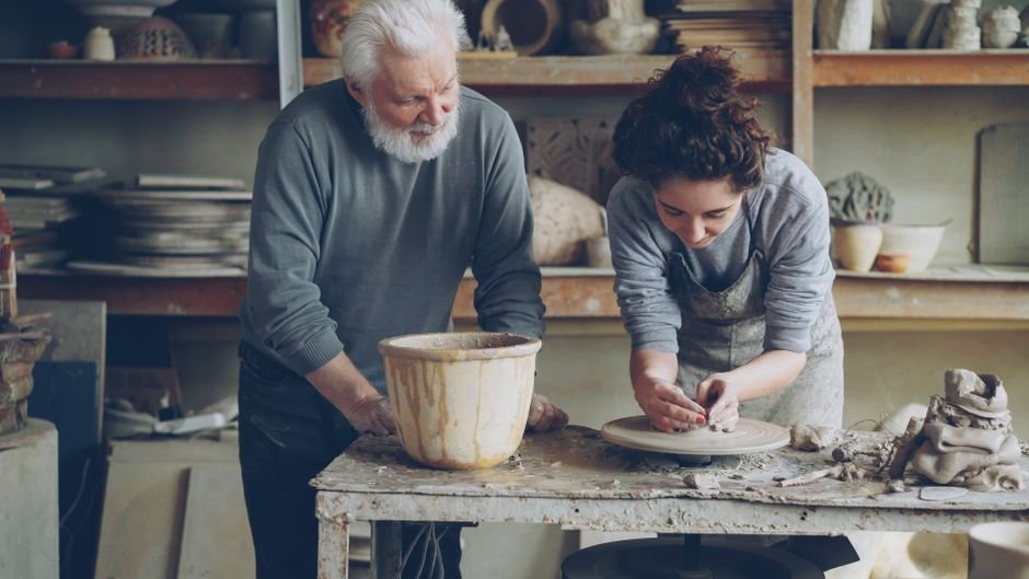 Pottery teacher guiding a student, a sign of good pottery wheel classes near you
