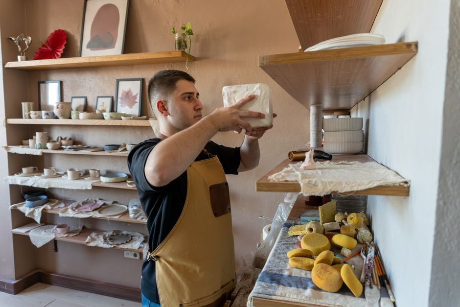 Potter arranging ceramic pieces on studio shelves, a routine part of a pottery studio membership
