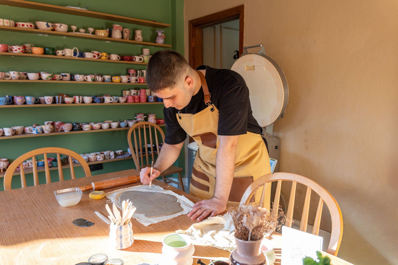 Potter wearing an apron while wheel throwing wet clay