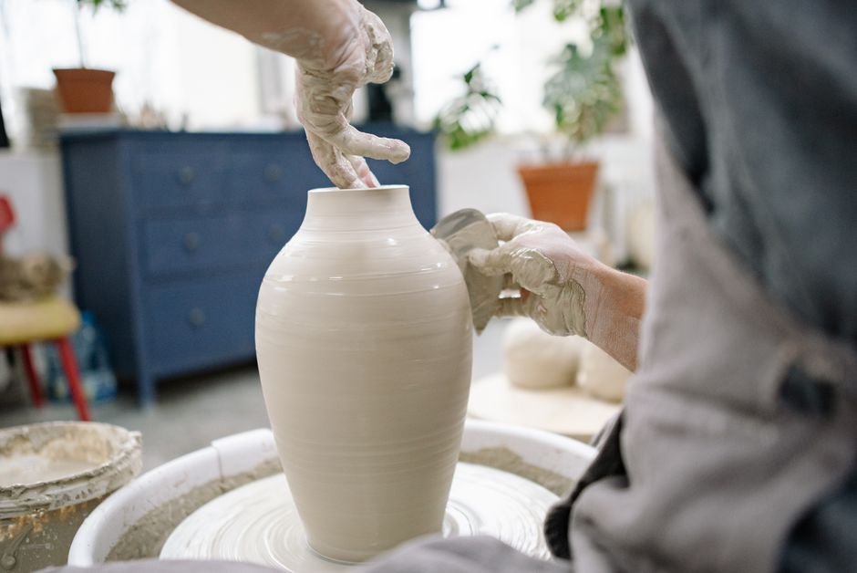 Potter shaping a vase on a wheel while keeping walls strong to avoid a pot collapsing on the wheel
