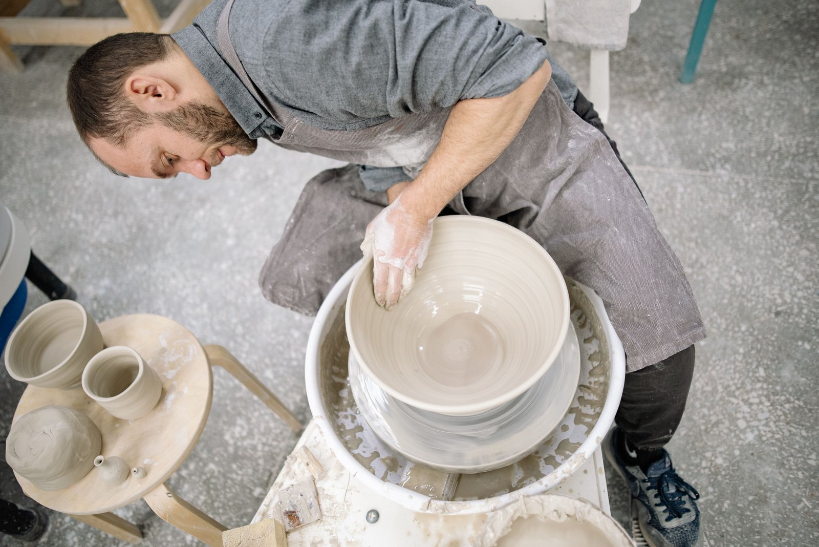 Person focused and calm while working with clay on a pottery wheel